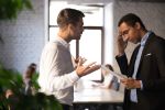 Angry Caucasian boss shouting at stressed African American employee, visual concept for workplace retaliation, harassment and bullying.