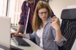 Businessman sexualy harassing female colleague during working hours at a workplace.
