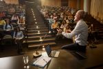 Professor speaking in front of large group of his students during a lecture in amphitheater. Visual concept for blog discussing whistleblowing in education exposing fraud in schools and universities.
